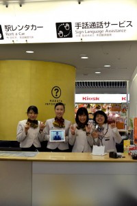 福岡市観光案内所・手話通話サービスの看板とスタッフの方の笑顔が目印です